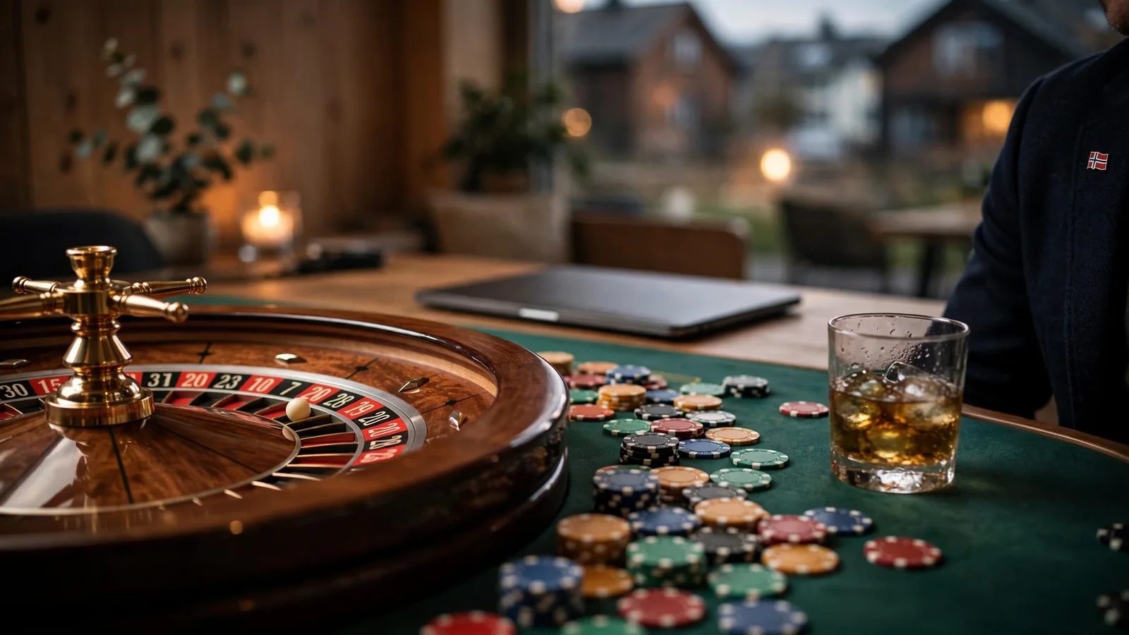 Roulettehjul med jetonger og laptop på et casino-inspirert bord